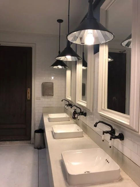 about-us Personne anonyme portant des gants en caoutchouc jaunes, utilisant une simple éponge pour nettoyer un miroir dans une salle de bain
